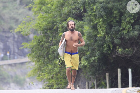 Paulinho Vilhena segura prancha a caminho da praia