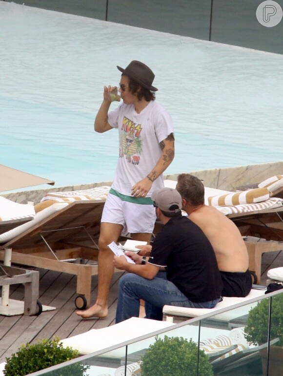 Harry Styles bebe capirinha em piscina de hotel