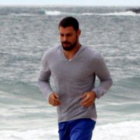 Sozinho, Cauã Reymond faz exercícios em areia de praia carioca