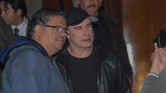 John Travolta atende fãs na porta do hotel onde está hospedado em São Paulo