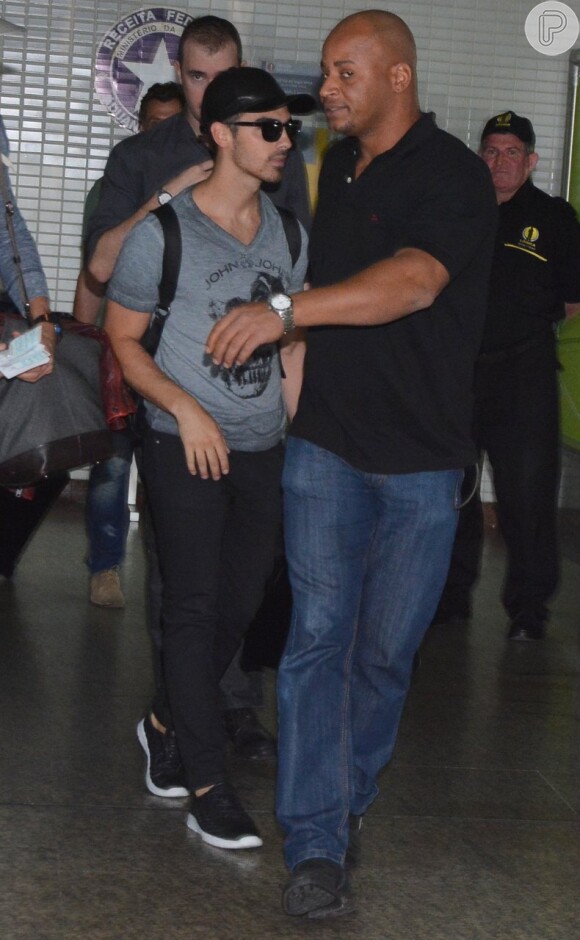 Joe Jonas contou com a ajuda de seguranças para deixar o aeroporto de São Paulo, nesta quarta-feira, 20 de agosto de 2014