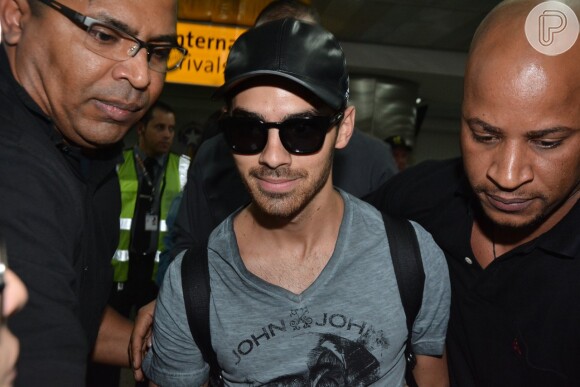 Joe Jonas precisou da escolta de seguranças para conseguir escapar do assédio dos fãs no aeroporto de Guarulhos, em São Paulo, na tarde desta quarta-feira, 20 de agosto de 2014