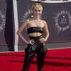 Miley Cyrus combina uma cropped top de couro com uma calça de cintura alta no mesmo tecido no tapete vermelho do VMA 2014
