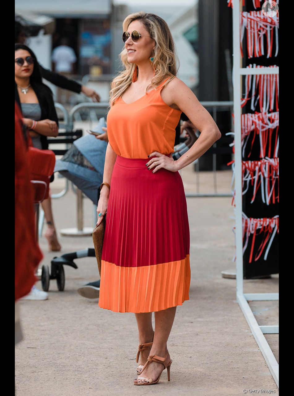 mulher usando blusa sem mangas e saia midi plissada de duas cores