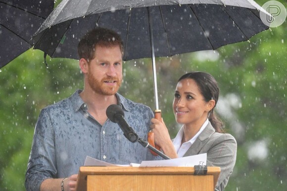Ainda na viagem à Austrália, Meghan Markle chamou atenção ao segurar guarda-chuva para o marido, príncipe Harry