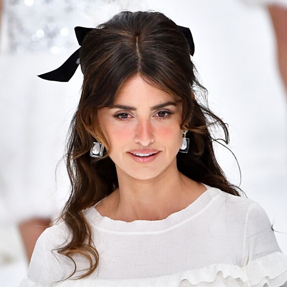 Retrô: Penélope Cruz usou penteado semi-preso com topete e laço de fita preto no desfile de outono/inverno da Chanel