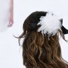 A presilha com tule e plumas brancas presa junto ao laço de fita preto foi destaque nos cabelos das modelos da Chanel