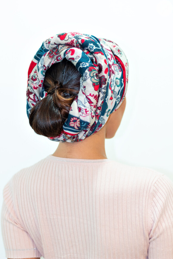 Penteado com turbante: Torça o turbante enquanto enrola o acessório em volta no couro cabeludo até que as pontas estejam bem atrás da cabeça.
