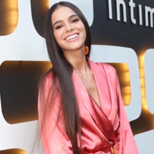 Bruna Marquezine surge com as mãos na cintura à espera do segurança revistar sua mala em aeroporto