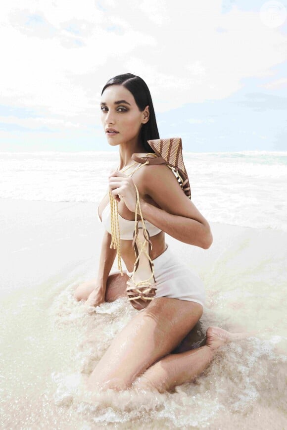 Débora Nascimento posa no mar de Barra de São Miguel, em Alagoas, segurando sandália anabela com amarrações 