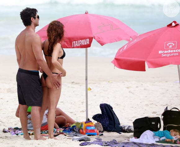 Isis Valverde ganha abraço do marido, André Resende, em dia de praia