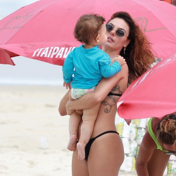Isis Valverde segura o filho, Rael, no colo, em dia de praia no Rio