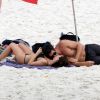 Isis Valverde, deitada na praia, ganha beijo do marido, André Resende