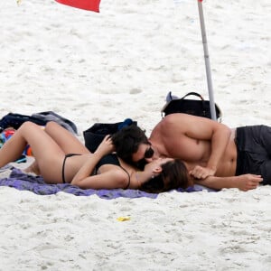 Isis Valverde, deitada na praia, ganha beijo do marido, André Resende