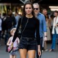 Moda verão 2020: short jeans preto curtinho, bota western e blusa com recortes nos ombros são opções para look fashion