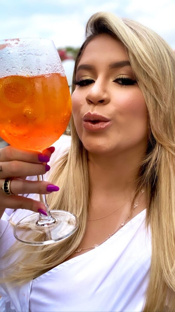 Marília Mendonça, decotada, posa com drink em foto