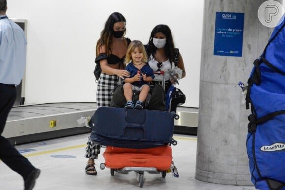 Filho de Isis Valverde fica risonho durante desembarque no Rio