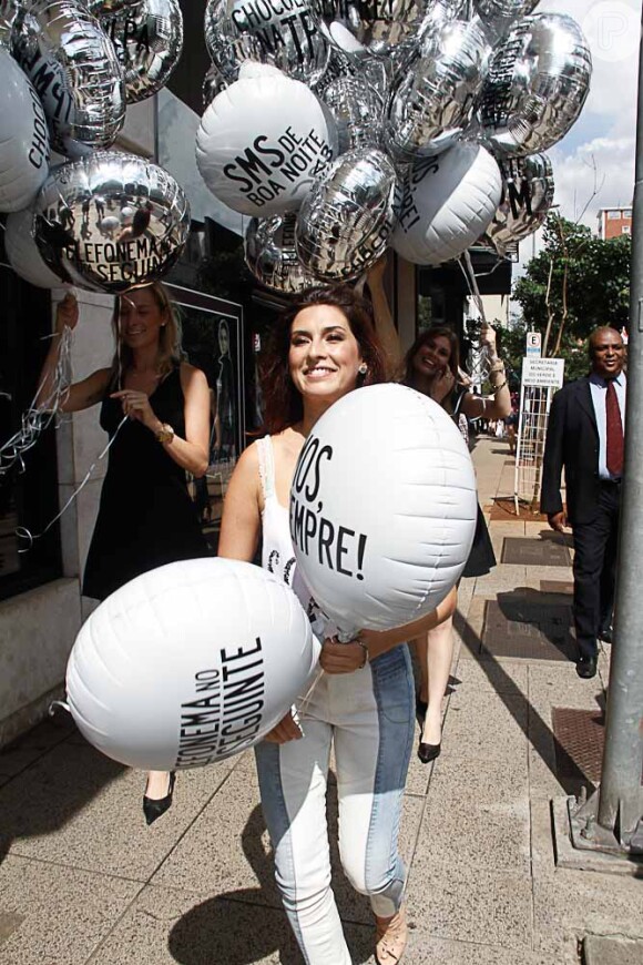 Fernanda Paes Leme carrega balões com diversas frases inspiradas nas que as mulheres dizem, como 'SMS de boa noite' e 'telefonema no dia seguinte'