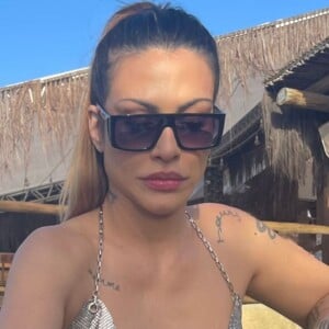 Cleo aparece com blusa prateada com correntes e decote profundo
