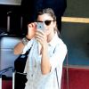 Grazi Masafera usa celular para fotografar paparazzo enquanto é clicada pelo profissional