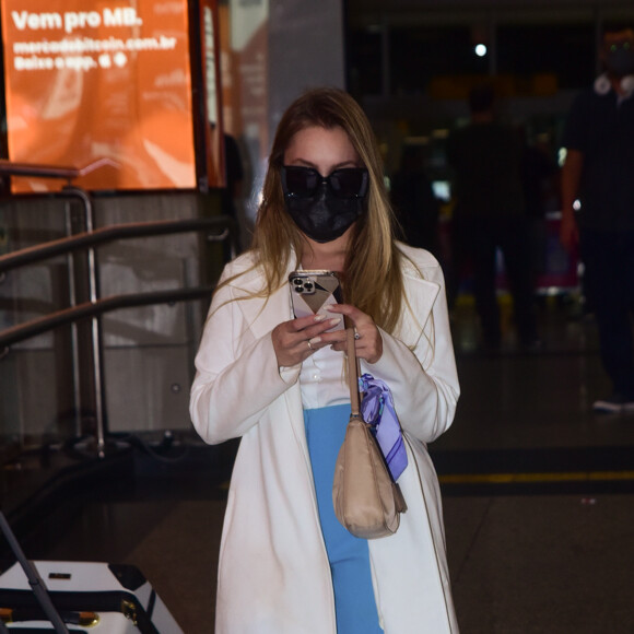 Carla Diaz mexe no celular ao desembarcar em aeroporto de São Paulo
