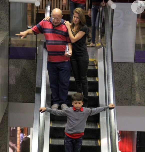 Nívea Stelmann se apoia no pai, Francisco, enquanto desce as escadas; seu filho, Miguel, vai logo à frente