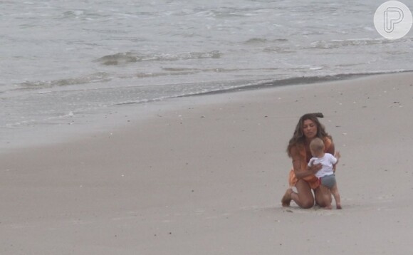 A atriz Grazi Massafera brinca com o bebê na areia da praia da Restinga da Marambaia