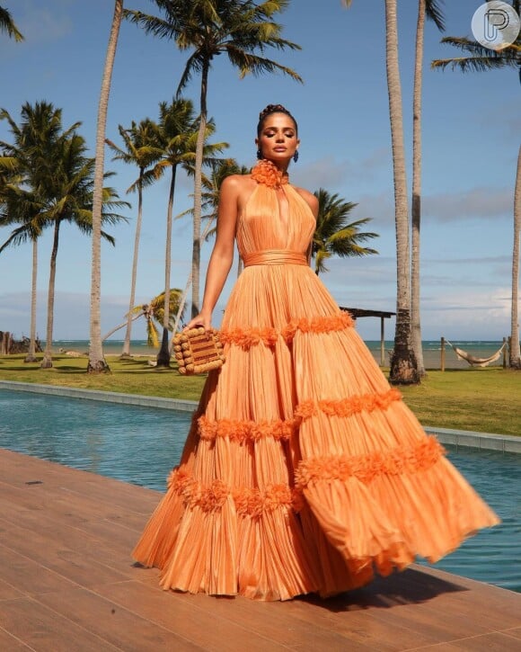 Vestido laranja para convidada para casamento na praia: Thássia Naves escolheu um look acinturado e combinou com bolsa de madeira
