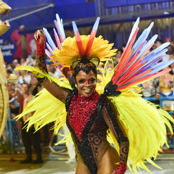 Adriana Bombom usou um look preto transparente com detalhes em vermelho e muitas plumas e penas nas costas