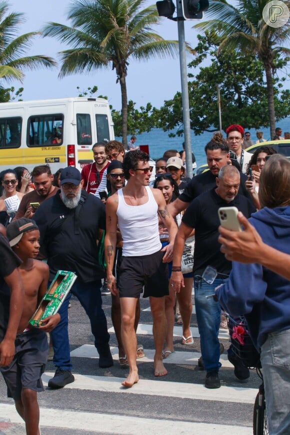 Com sorrisão no rosto, Shawn Mendes vai à praia de Ipanema e é cercado por uma multidão de fãs. Veja fotos!