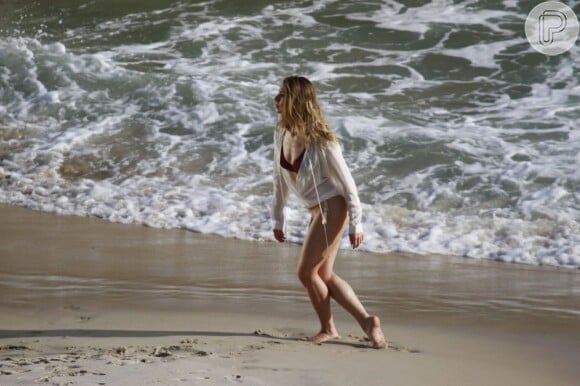 Feliz, ela fotografa para revista em praia do Rio