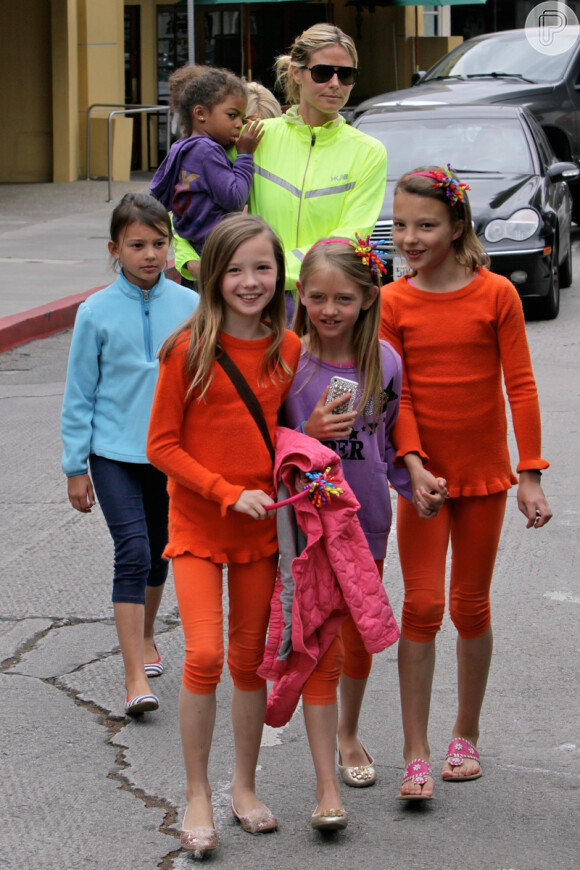 Heidi Klum carrega sua filha Lou Klum Samuel, de 3 anos, enquanto sua outra, Leni Klum, de 8, com casaco lilás, anda à frente da mãe