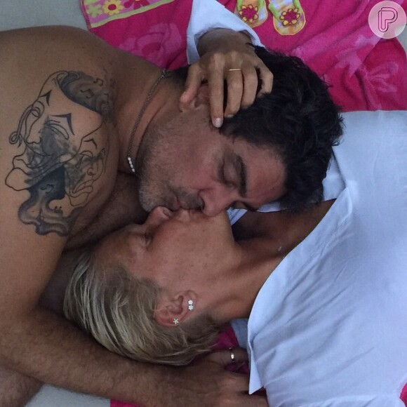 Xuxa publicou uma foto beijando Junno Andrade em seu Facebook e o ator e cantor deixou à mostra sua tatuagem