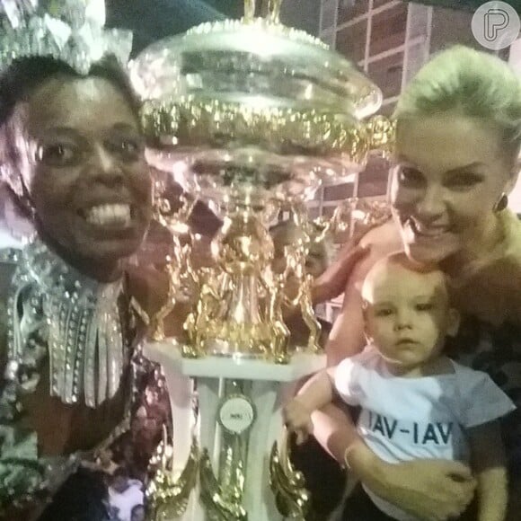 Com o filho, Alexandre Jr., no colo, Ana Hickmann posa ao lado do troféu que a Vai-Vai recebeu por ser a campeã do Carnaval de São Paulo