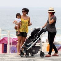 Grávida, Carolina Ferraz empurra carrinho de bebê da amiga em passeio na praia