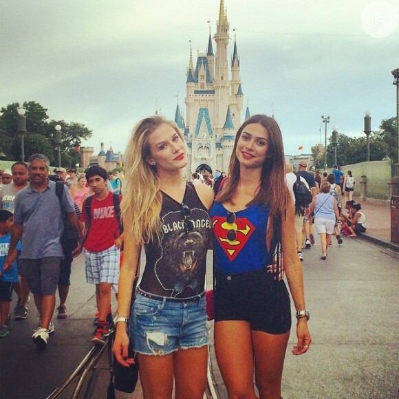 De short preto e blusa do superman franjada, a atriz posa ao lado de Fiorella Mattheis na Disney