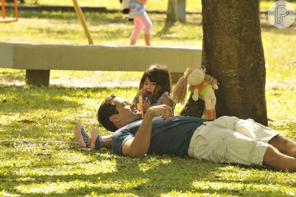 Deitado no colo da filha, Bruno (Malvino Salvador) segura um boneca de pano, em cena de 'Amor à Vida'