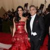 Acompanhada do marido, George Clooney, Amal escolheu um vestido vermelho chamativo da grife John Galliano