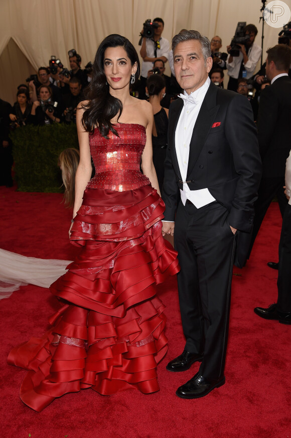 Acompanhada do marido, George Clooney, Amal escolheu um vestido vermelho chamativo da grife John Galliano