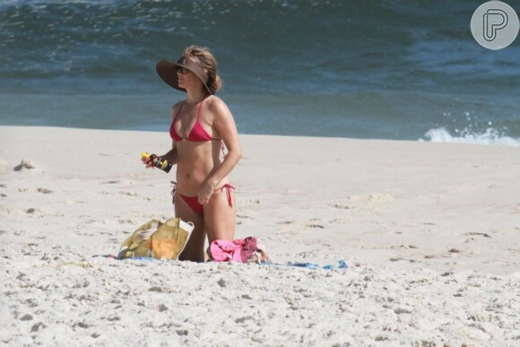 Christine Fernandes ajeita o biquíni e passa bronzeador em praia do Rio