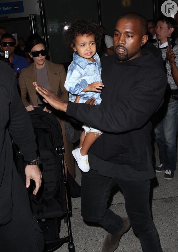 Em outro clique, no colo do pai, Kanye West, North West mostra personalidade com um look total jeans