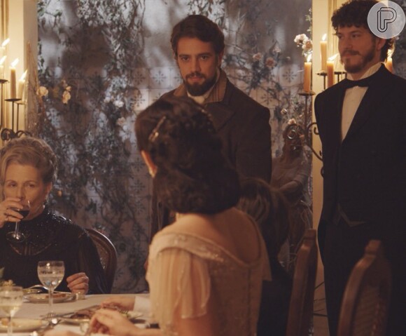 Felipe (Rafael Cardoso) se surpreende quando chega em casa e vê Alex (Kadu Schons) à mesa, na novela 'Além do Tempo'