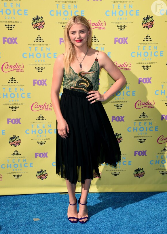Chloë Grace Moretz apostou em conjunto de saia maxi preta e top de renda verde, com desenho de uma cobra para o Teen Choice Awards 2015. A atriz completou o look com sandálias roxas