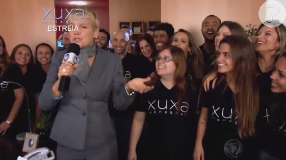 Xuxa ganha a companhia de sua equipe, que entra na sala cantando 'Vamos com você, nós somos invencíveis, pode crer'
