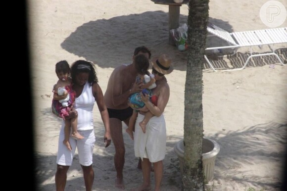 Giovanna Antonelli segura uma das filhas no colo, enquanto o marido beija a menina