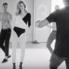 Com um collant preto e branco e uma ankle boot preta, Gisele Bündchen é coreografada e dança ao lado de vários rapazes sem camisa