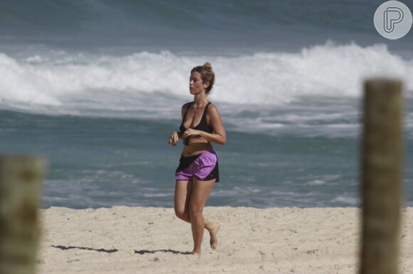 Juliana Didone usa shortinho e top para correr na praia da Barra, RJ