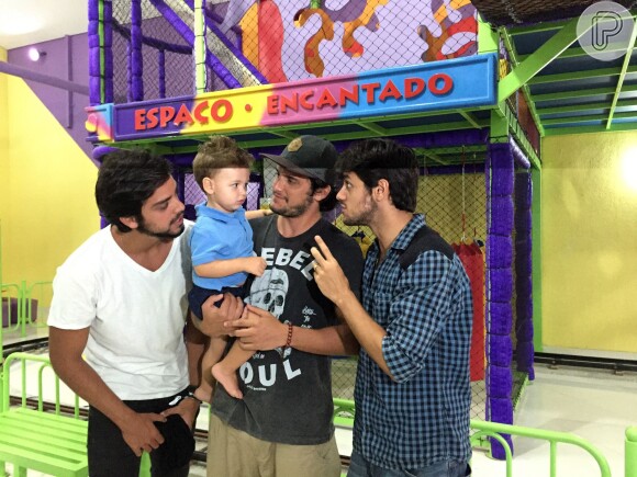 Joaquim posa no colo do tio Bruno Gissoni e é observado pelo outro tio, Rodrigo Simas, enquanto interagem com o papai