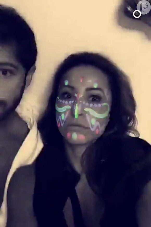 O casal aparece na cama brincando com efeitos especiais no Snapchat