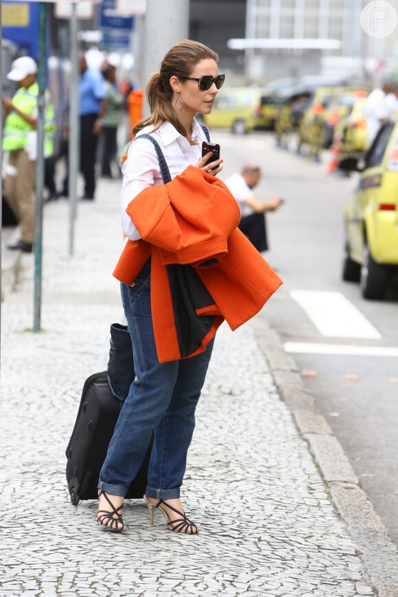 Paolla Oliveira carrega seu casaco laranja ao desembarcar em aeroporto do Rio